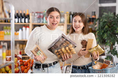 Two girls in store while shopping, choose sweets and chat sweetly Two girls in store while shopping, choose sweets and chat sweetly 121309282