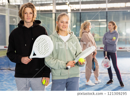 Portrait of guy and girl on an open court playing padel 121309295