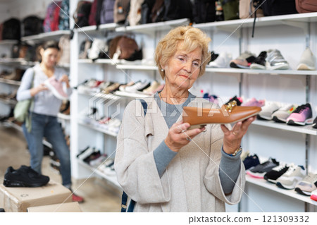 Elderly woman selecting footwear in shoeshop Elderly woman selecting footwear in shoeshop 121309332