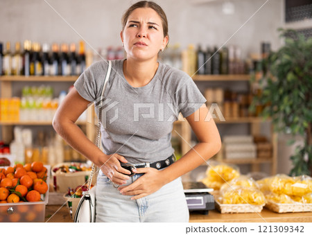 Young woman with stomach pain in grocery store Young woman with stomach pain in grocery store 121309342