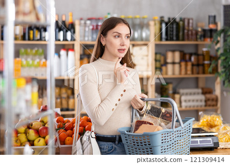 Young woman choosing food in grocery store 121309414