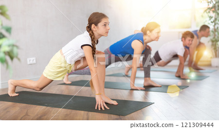 Family with son and daughter practicing yoga in virabhadrasana pose in gym Family with son and daughter practicing yoga in virabhadrasana pose in gym 121309444