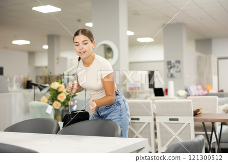Girl buyer choose dining table desk in furniture store showroom 121309512