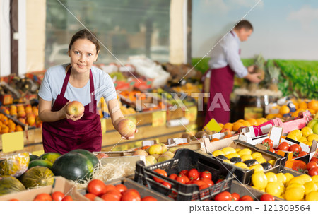 Smiling female vendor offering ripe apples at farmers market 121309564