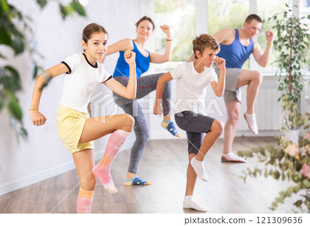 Happy preteen boy and girl practicing dance movements with their parents 121309636