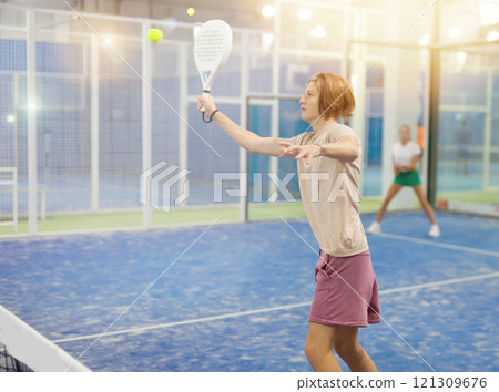 Teenage boy playing padel in court Teenage boy playing padel in court 121309676