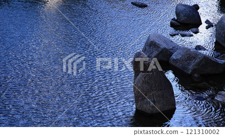 A Japanese garden filled with a wabi-sabi atmosphere, where the reflection of light and rocks create beautiful ripples on the water surface A Japanese garden filled with a wabi-sabi atmosphere, where the reflection of light and rocks create beautiful ripples on the water surface 121310002