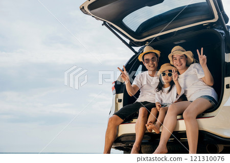 Family Day. Happy people having fun in summer vacation on beach, Family traveling in holiday at sea beach, Dad, mom and children daughter enjoying road trip sitting on back car showing V-sign signal 121310076