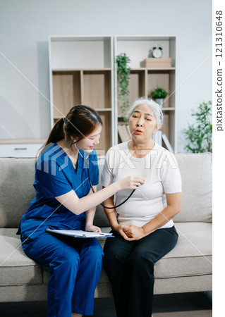 Asian caregiver doctor examine older patient woman therapist nurse at nursing home taking care of senior elderly woman sit on sofa.Medical service concept. Asian caregiver doctor examine older patient woman therapist nurse at nursing home taking care of senior elderly woman sit on sofa.Medical service concept. 121310648