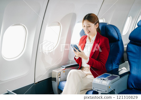 Young Asian executive excels in first class, multitasking with digital tablet, laptop and smartphone. Travel in style, work 121310829