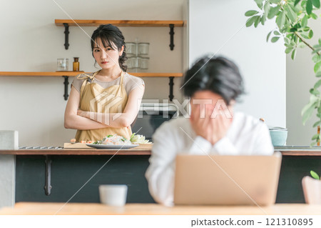 家庭主婦/妻子不滿地瞪著在家廚房工作的丈夫(夫妻吵架、惱怒、離婚) 家庭主婦/妻子不滿地瞪著在家廚房工作的丈夫(夫妻吵架、惱怒、離婚) 121310895