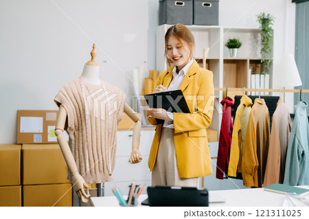 Asian tailor woman working on clothes in tailoring atelier. beautiful young female fashion designer smile 121311025
