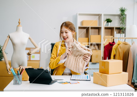 Asian tailor woman working on clothes in tailoring atelier. beautiful young female fashion designer smile Asian tailor woman working on clothes in tailoring atelier. beautiful young female fashion designer smile 121311026