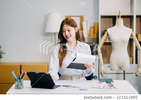 Fashion designer woman talking smart phone and using laptop with digital tablet computer in modern studio Fashion designer woman talking smart phone and using laptop with digital tablet computer in modern studio 121311095