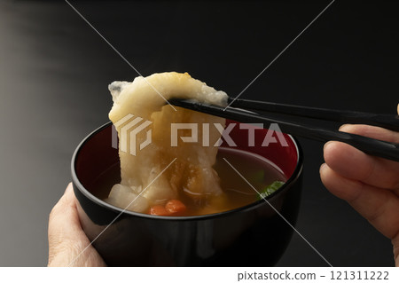將碗放在手中，然後用筷子夾起麻糬。 121311222