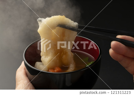 將碗放在手中，然後用筷子夾起麻糬。 121311223