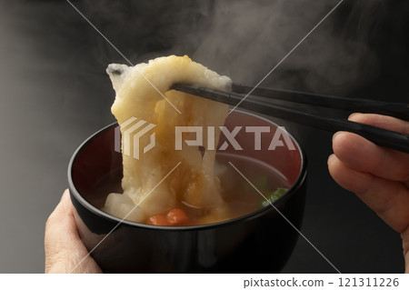 Hold the bowl of ozoni in your hands and lift the mochi with chopsticks Hold the bowl of ozoni in your hands and lift the mochi with chopsticks 121311226