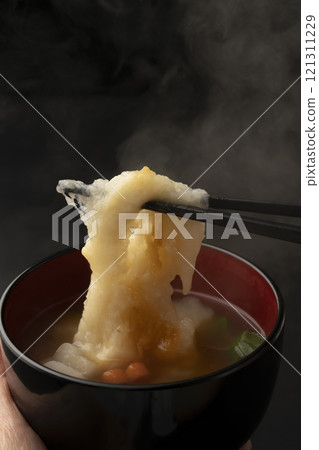將碗放在手中,然後用筷子夾起麻糬。 將碗放在手中,然後用筷子夾起麻糬。 121311229