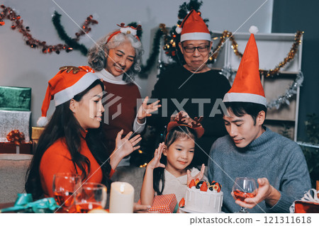 Multi-Generation Family Celebrate Christmas At Home Wearing Santa Hats And Antlers Opening Presents Multi-Generation Family Celebrate Christmas At Home Wearing Santa Hats And Antlers Opening Presents 121311618