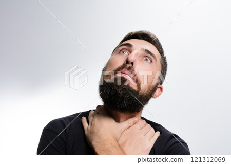 Man with beard looks up with worried expression, hands on neck. 121312069