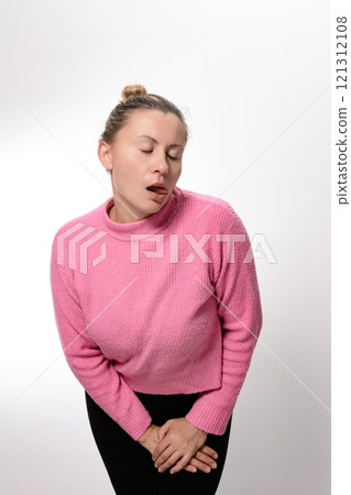 Woman in pink sweater and black pants holding her crotch with closed eyes and tongue out. 121312108