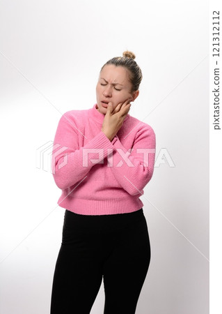 Woman experiencing toothache, holding her jaw in pain. 121312112