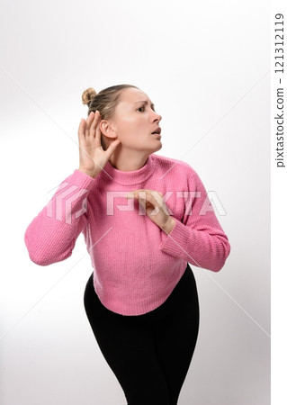 Woman cupping hand to ear, listening intently. 121312119