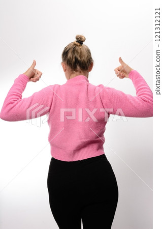 Woman in pink top and black leggings, thumbs up, back view. 121312121