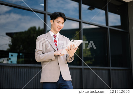 Young Asian businessman leader entrepreneur, professional manager holding digital tablet computer on the street in big city 121312695