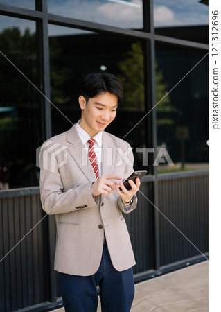 Young Asian businessman leader entrepreneur, professional manager holding digital tablet computer on the street in big city Young Asian businessman leader entrepreneur, professional manager holding digital tablet computer on the street in big city 121312696