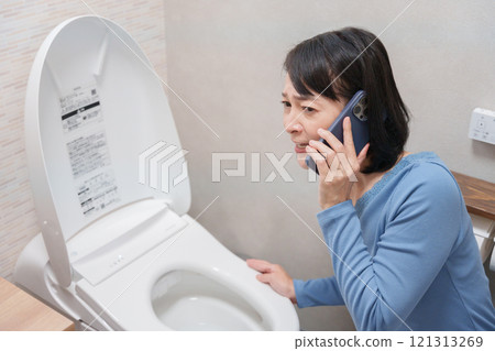 A woman calls a plumber about a toilet problem 121313269