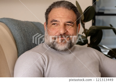 Smiling mature man relaxing at home, enjoying peaceful moment on sofa Smiling mature man relaxing at home, enjoying peaceful moment on sofa 121313449
