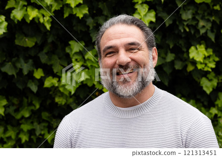 Smiling mature man outdoors, enjoying nature with lush green leaves in background Smiling mature man outdoors, enjoying nature with lush green leaves in background 121313451
