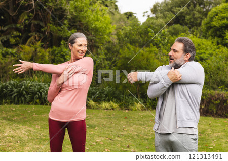 Mature couple stretching arms outdoors, smiling and enjoying exercise together Mature couple stretching arms outdoors, smiling and enjoying exercise together 121313491
