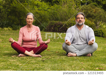 Mature couple meditating outdoors on grass, finding peace and relaxation together Mature couple meditating outdoors on grass, finding peace and relaxation together 121313493