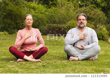 Mature couple meditating outdoors, practicing mindfulness and relaxation in nature 121313495