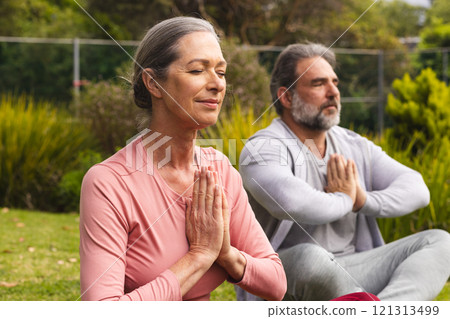 Mature couple meditating outdoors, finding peace and relaxation in nature 121313499
