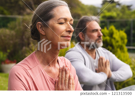Mature couple meditating outdoors, enjoying peaceful moment in nature together Mature couple meditating outdoors, enjoying peaceful moment in nature together 121313500