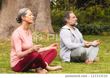 Meditating outdoors, mature couple experiencing peaceful moment in nature together 121313510