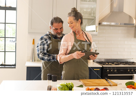 Mature couple cooking together in kitchen, using tablet for recipe inspiration, at home Mature couple cooking together in kitchen, using tablet for recipe inspiration, at home 121313557