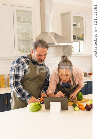 Mature couple cooking together in kitchen, following recipe on tablet, at home Mature couple cooking together in kitchen, following recipe on tablet, at home 121313561