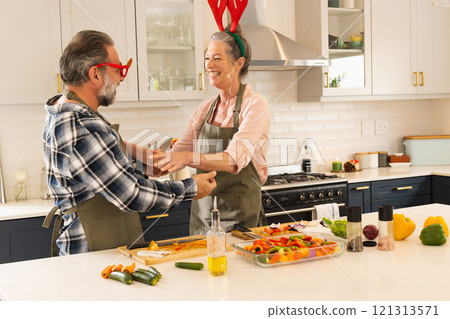 Christmas time, Mature couple in kitchen laughing and preparing festive meal together, at home Christmas time, Mature couple in kitchen laughing and preparing festive meal together, at home 121313571