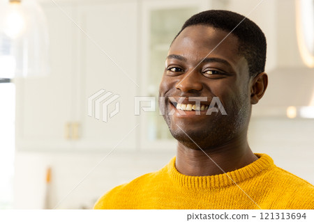 Smiling African american man in yellow sweater enjoying festive holiday spirit at home, copy space Smiling African american man in yellow sweater enjoying festive holiday spirit at home, copy space 121313694