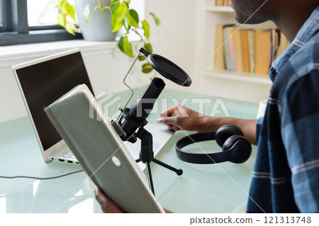 African American man recording podcast at home with microphone and laptop 121313748