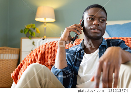 Relaxing at home, African American man talking on smartphone, feeling comfortable Relaxing at home, African American man talking on smartphone, feeling comfortable 121313774