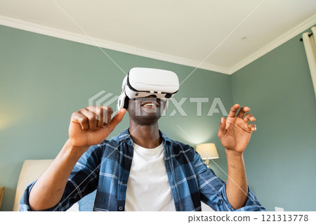 African American man enjoying virtual reality headset experience at home 121313778