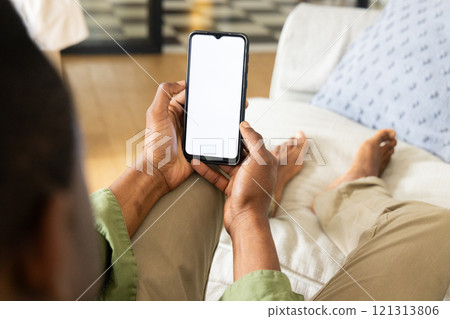 Relaxing at home, African American man using smartphone on couch, copy space Relaxing at home, African American man using smartphone on couch, copy space 121313806