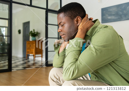 African American man sitting at home, appearing thoughtful and introspective African American man sitting at home, appearing thoughtful and introspective 121313812