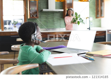 African american boy having online class using headphones and laptop with copy space, slow motion 121314185