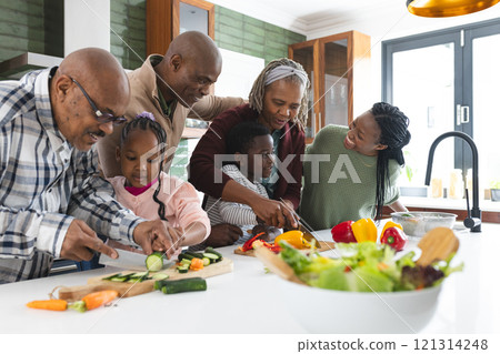 Happy african american multi generation family chopping vegetables in kitchen, slow motion 121314248